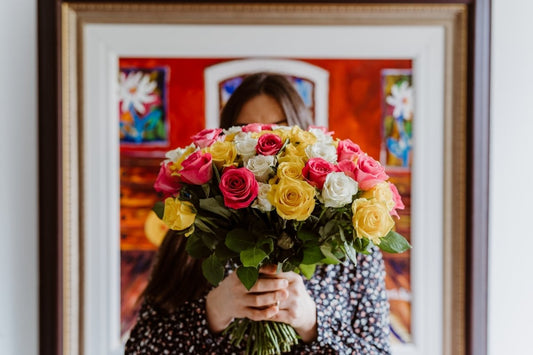 An image of a girl with a bouquet of flowers in her hand covering her face